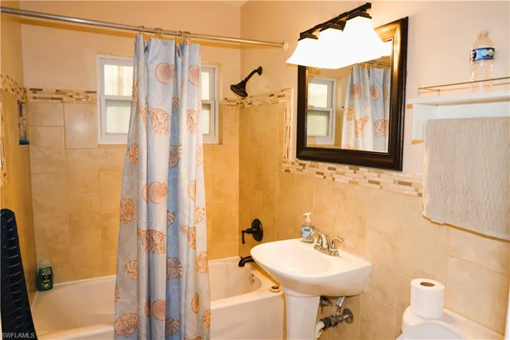 Full bathroom with shower / bath combo and tile walls