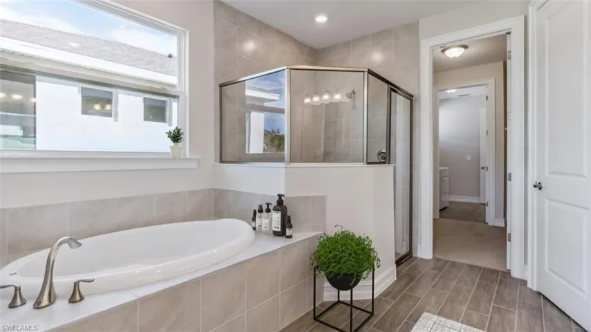 This image is virtually staged. Bathroom with a shower stall, a bath, and wood tiled floors