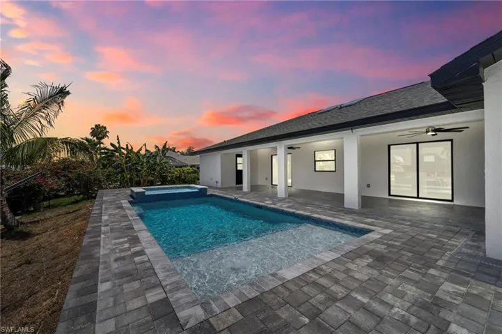 Pool at dusk featuring a patio, ceiling fan, and an in ground hot tub