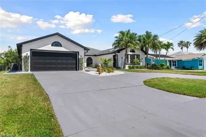 Ranch-style house with curved driveway, an attached garage, a front lawn, and stucco siding