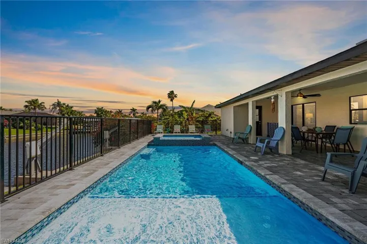 View of pool featuring a patio area, fence, a pool with connected hot tub, and a ceiling fan