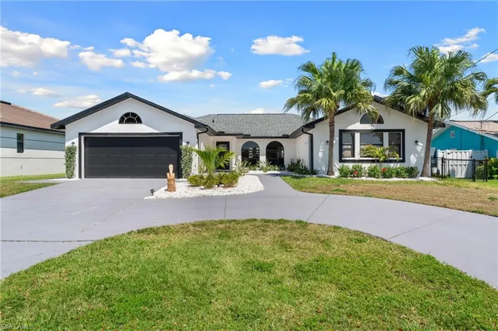 Ranch-style house with an attached garage, curved driveway, stucco siding, and a front yard