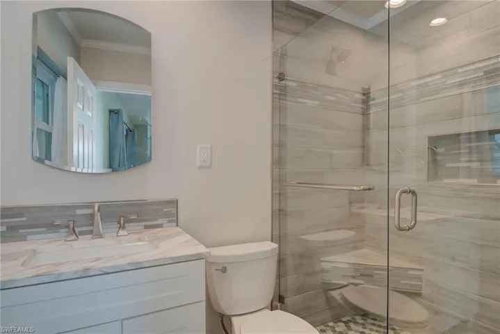 Full bath featuring ornamental molding, vanity, and a stall shower