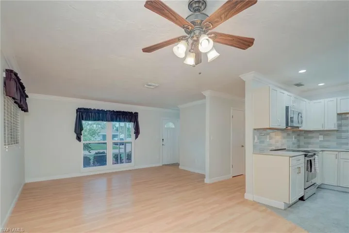 Kitchen featuring decorative backsplash, white cabinets, ornamental molding, white range with electric stovetop, and light wood-style floors