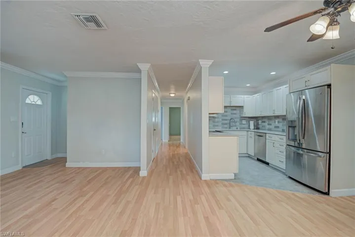 Kitchen with appliances with stainless steel finishes, light countertops, white cabinets, open floor plan, and decorative backsplash