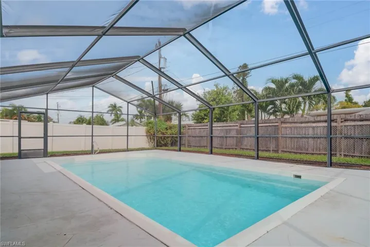 View of swimming pool featuring a fenced backyard, glass enclosure, and a sunroom