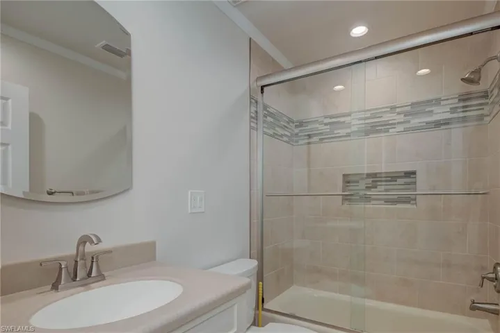 Full bath featuring bath / shower combo with glass door, vanity, and crown molding