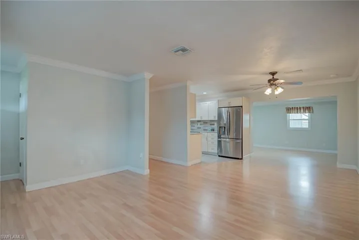 Unfurnished living room with ornamental molding, light wood-type flooring, and ceiling fan