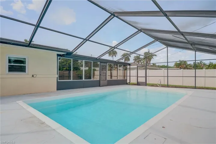 View of swimming pool with a sunroom, glass enclosure, and a patio