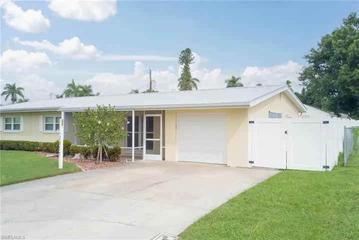 Ranch-style home with an attached garage, a gate, stucco siding, driveway, and a sunroom