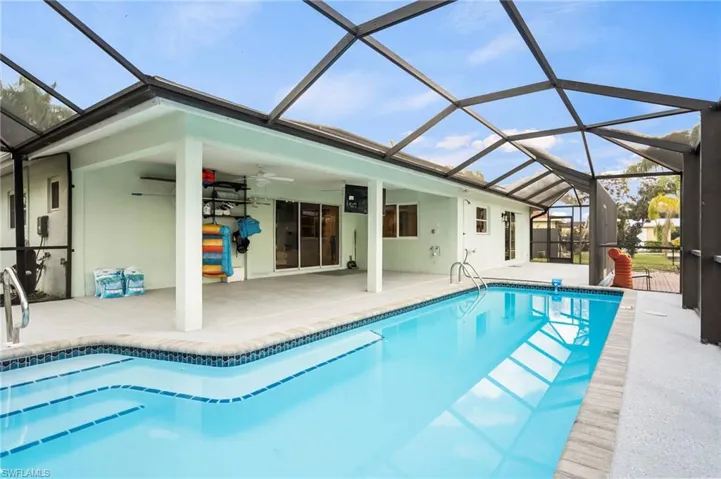 View of swimming pool featuring a patio, ceiling fan, and glass enclosure