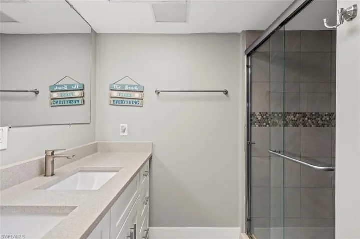 Bathroom featuring a shower with door and vanity
