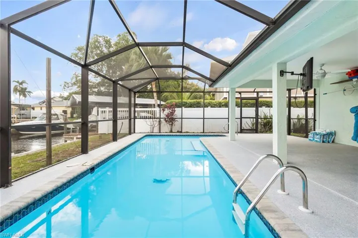 View of swimming pool with ceiling fan, glass enclosure, and a patio area