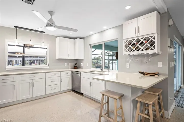Kitchen featuring white cabinetry, a breakfast bar area, kitchen peninsula, and dishwasher