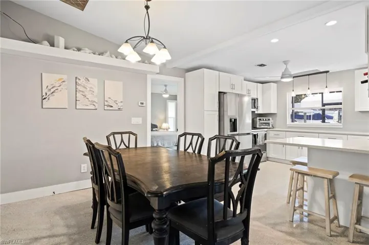 Dining space with beam ceiling and ceiling fan with notable chandelier
