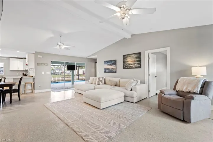 Living room with lofted ceiling with beams and ceiling fan