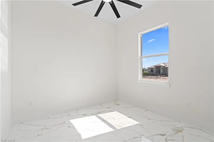 Unfurnished room with marble look tile flooring and baseboards