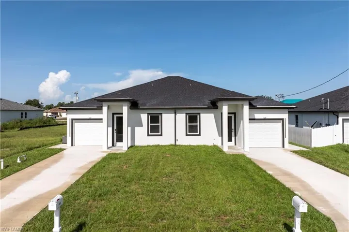 View of front of property featuring stucco siding, a garage, a shingled roof, and driveway