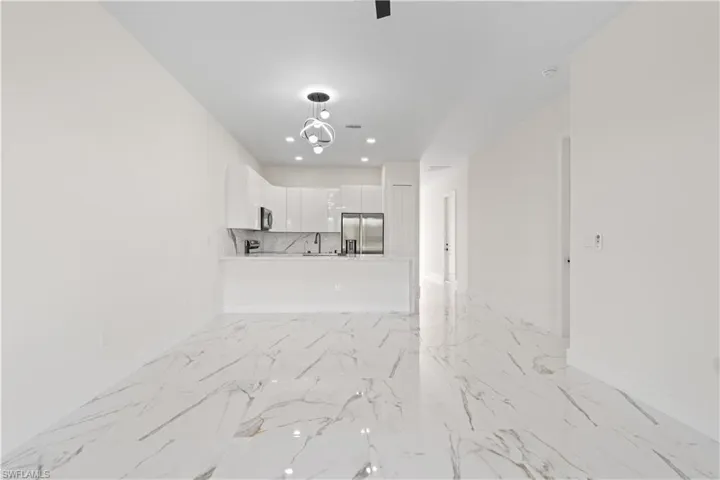 Unfurnished living room with light marble finish floors and recessed lighting