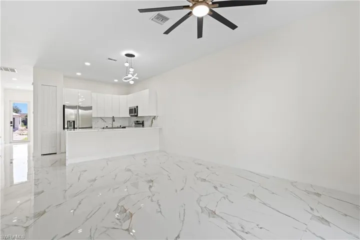 Unfurnished living room with light marble finish flooring, recessed lighting, and ceiling fan