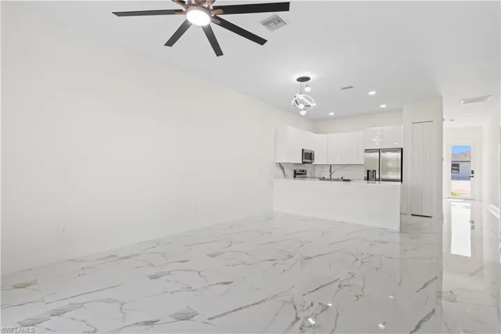Unfurnished living room featuring light marble finish floors, recessed lighting, and a ceiling fan