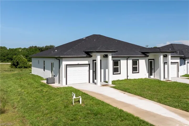 View of front of property with an attached garage, stucco siding, a front lawn, and driveway