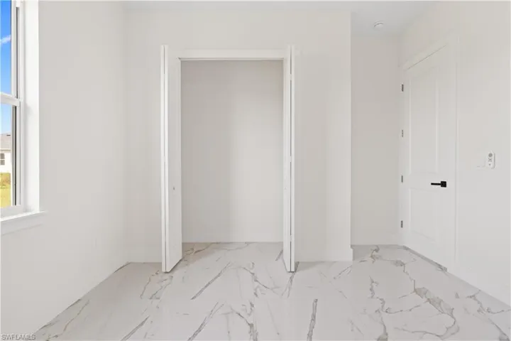 Unfurnished bedroom with light marble finish flooring and baseboards