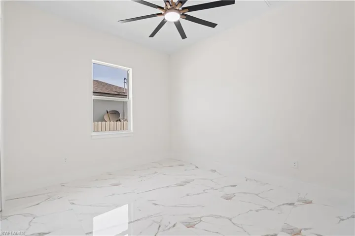 Spare room with marble look tiles and a ceiling fan