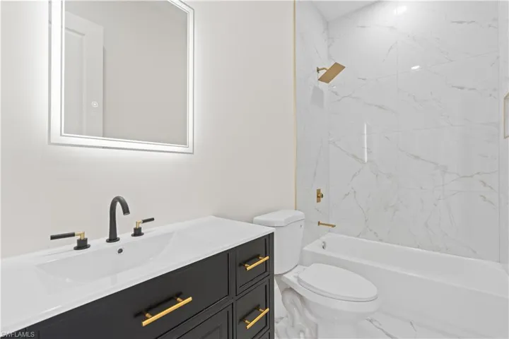 Bathroom with vanity, shower / tub combination, and marble look tile flooring