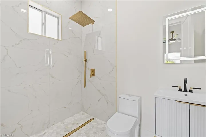Bathroom featuring a marble finish shower and vanity