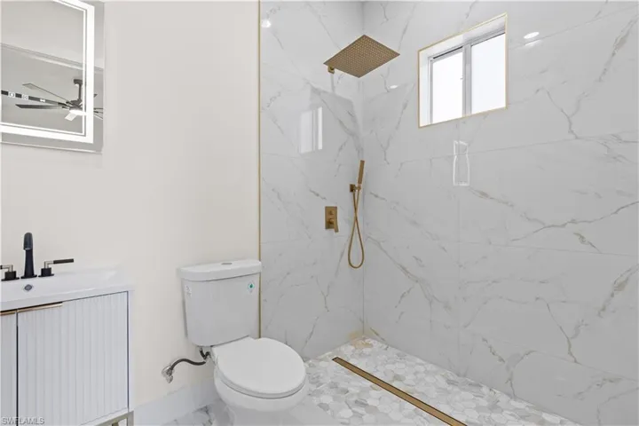 Full bath with vanity, a marble finish shower, and ceiling fan