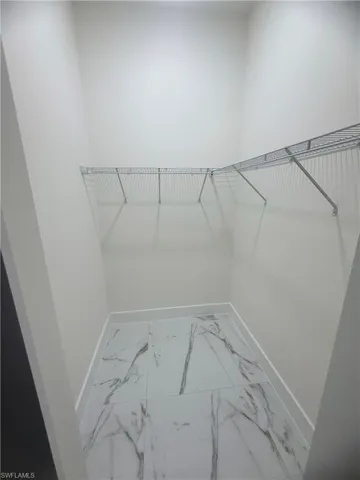 Walk in closet featuring light marble finish floors
