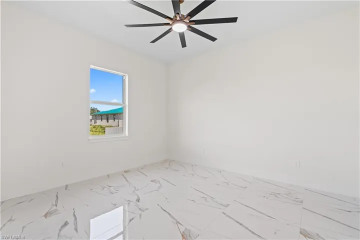 Unfurnished room featuring marble look tile flooring and ceiling fan