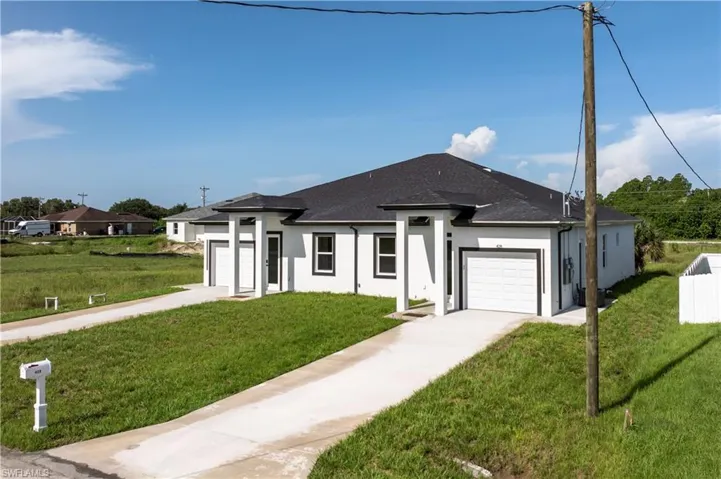 Prairie-style home with an attached garage, concrete driveway, stucco siding, and a front yard