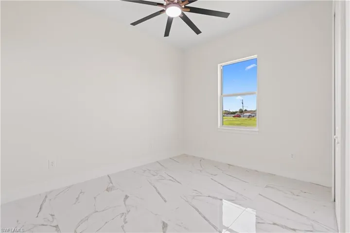Spare room featuring marble look tile flooring and baseboards