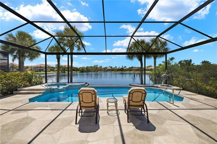 View of swimming pool with a patio area, glass enclosure, a pool with connected hot tub, and a water view