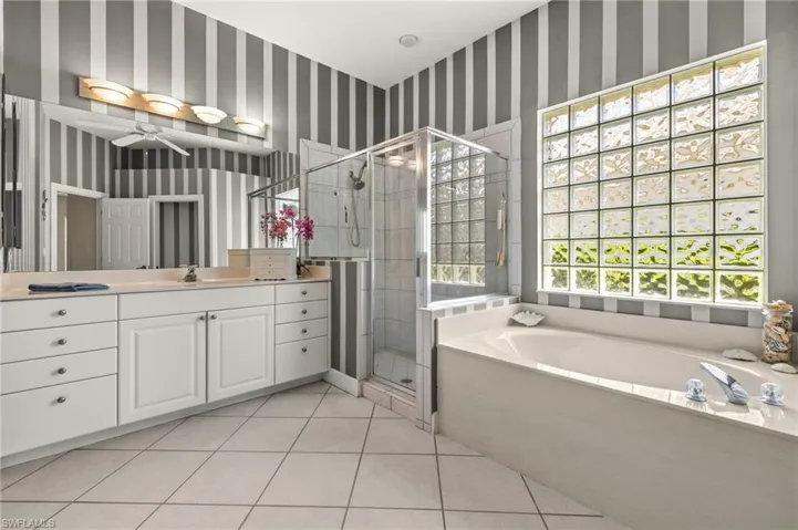 Bathroom with a shower stall, wallpapered walls, a bath, vanity, and tile patterned flooring