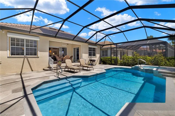 View of pool featuring glass enclosure, ceiling fan, a patio, and a pool with connected hot tub