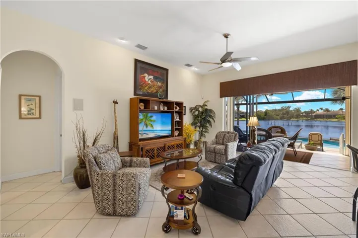 Living area with ceiling fan, arched walkways, light tile patterned flooring, and visible vents