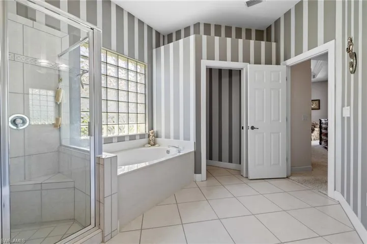 Bathroom with a bath, a stall shower, visible vents, wallpapered walls, and tile patterned flooring