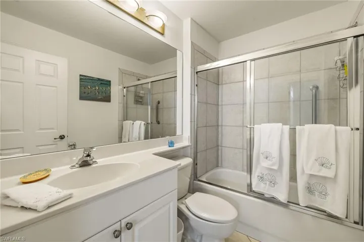 Bathroom with vanity, enclosed tub / shower combo, and toilet