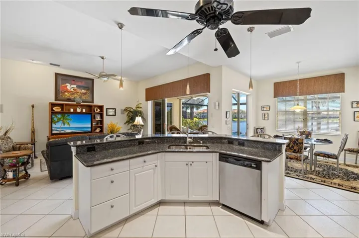 Kitchen featuring open floor plan, stainless steel dishwasher, a ceiling fan, and a sink
