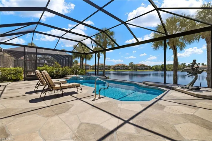 View of pool featuring a water view, glass enclosure, a pool with connected hot tub, and a patio