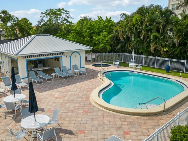 Community pool featuring a patio, an outbuilding, fence, and a hot tub