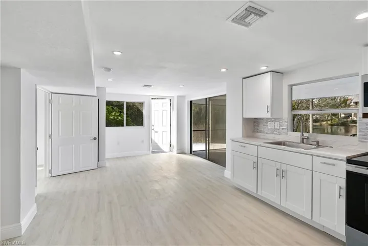 Apartment 1 Kitchen with white cabinetry, a healthy amount of sunlight, sink, and decorative backsplash