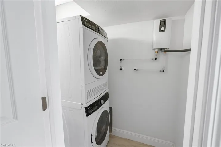 Apartment 1 Laundry room featuring stacked washer and dryer, light hardwood / wood-style floors, and water heater