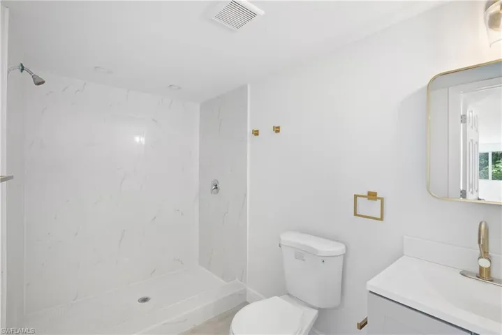 Apartment 1 Bathroom featuring vanity, toilet, and a tile shower