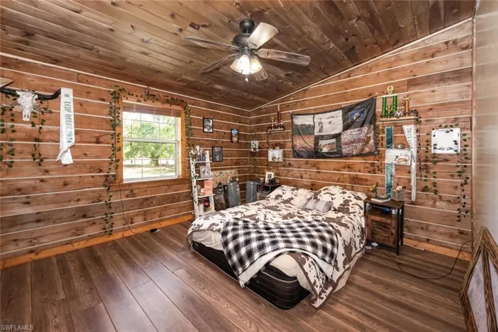 Bedroom with wood finished floors, wooden walls, wooden ceiling, and vaulted ceiling