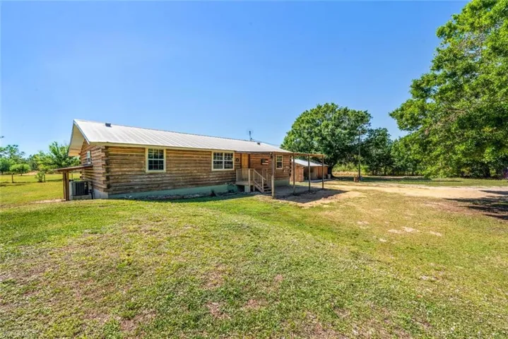 Back of house with a yard and log exterior