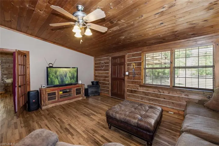 Living room with a ceiling fan, vaulted ceiling, wood finished floors, and wooden ceiling